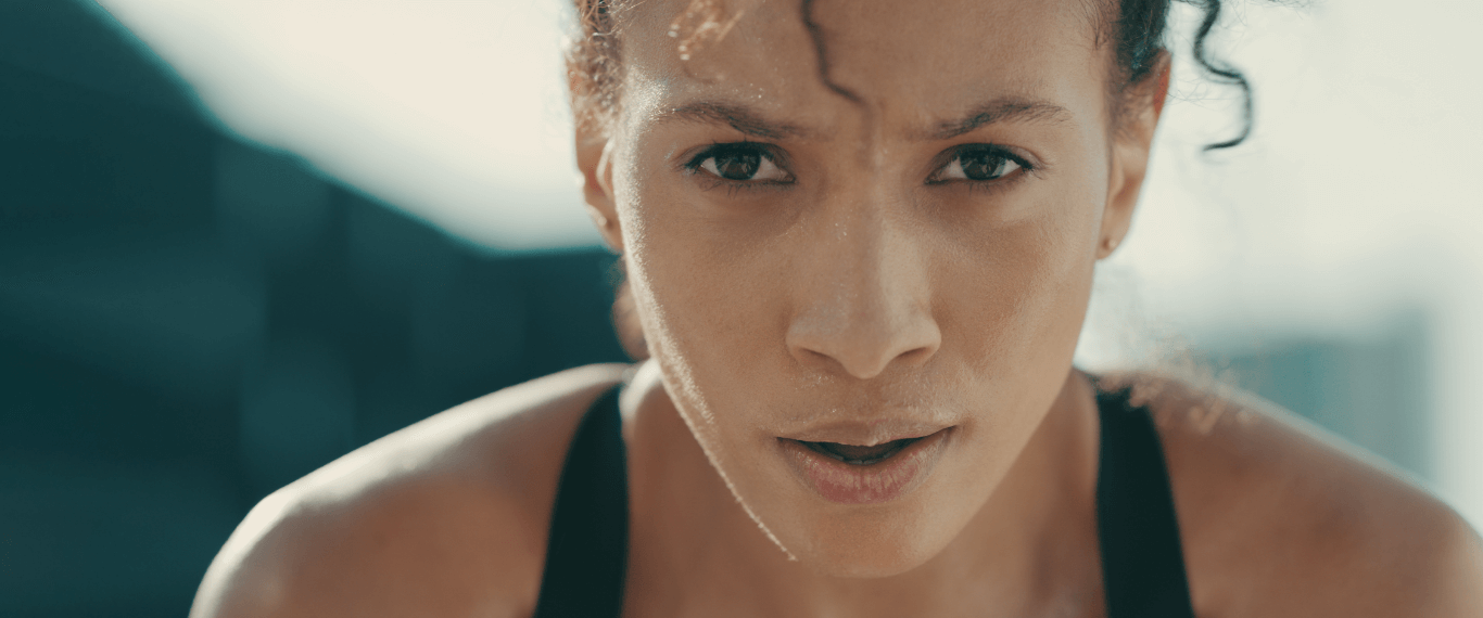 Woman about to do a physical challenge – a race or lifting weights. The close-up of her face shows her focusing her breathing